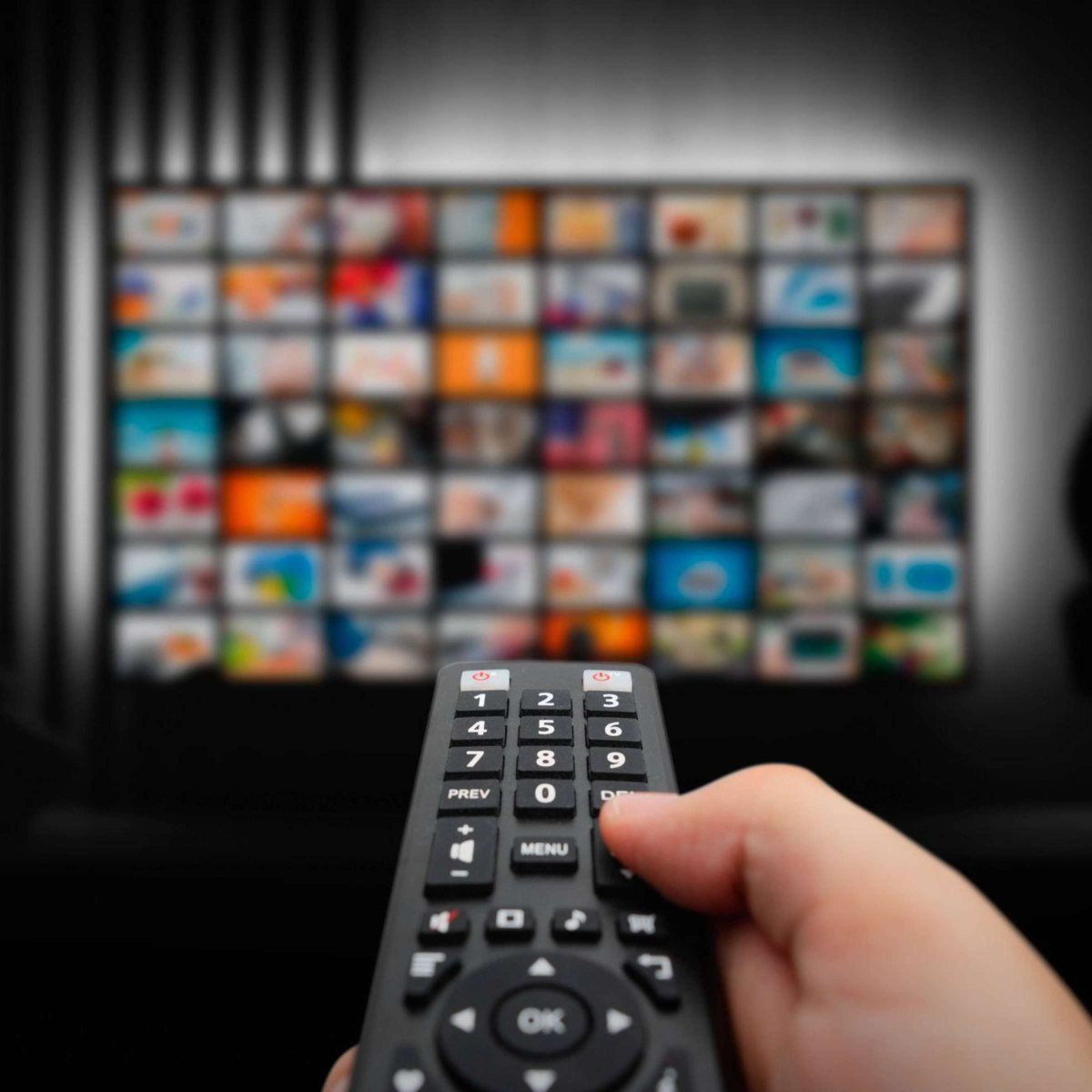 Elde kumanda, arkada kanal küçük resimleriyle dolu televizyon ekranı